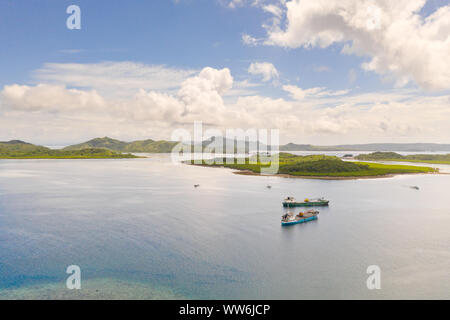 Cargo ships moored in a bay among tropical islands. Dapa Ferry Terminal. Siargao, Philippines. Philippine Islands. Stock Photo