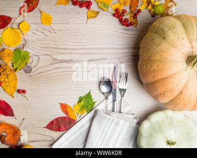 Autumn table setting, background from fallen leaves,apple.physalis, berries with vintage place setting on wooden table. Thanksgiving day concept Stock Photo