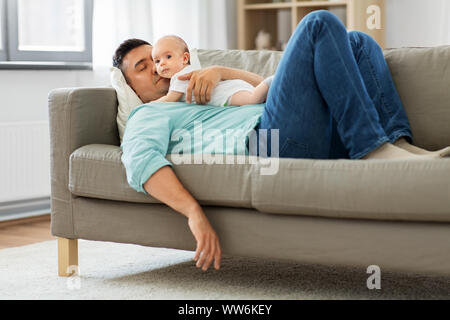 father with baby sleeping on sofa at home Stock Photo