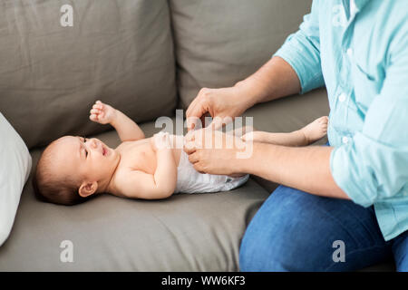 middle aged father changing baby's diaper at home Stock Photo