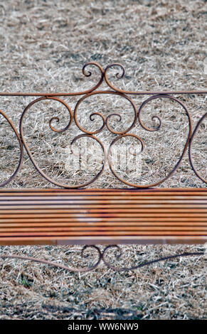 filigree rusty park bench in front of meadow area Stock Photo