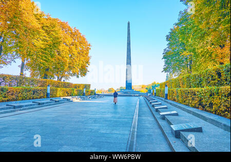 The alley with the memorial plates of the heroes of the WWII in Park of Eternal Glory with the stone Obelisk and Eternal Flame in Kyiv, Ukraine Stock Photo