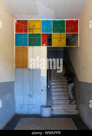 Eritrean girl in an old art deco style stairs from the italian colonial times, Central region, Asmara, Eritrea Stock Photo