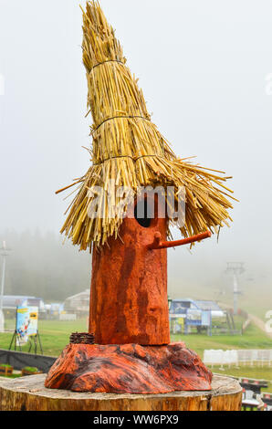 Homemade birdhouse, small log with pit and twig and roof made of straw, painted and decorated Stock Photo