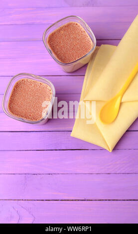 Chocolate Yogurt. Two portions of chocolate milk dessert are on a wooden table of purple. Stock Photo