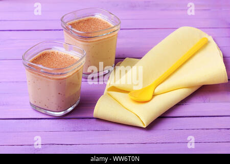 Chocolate Yogurt. Two portions of chocolate milk dessert are on a wooden table of purple. Stock Photo