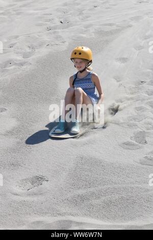 Closeup of a girl sand surfing down the Bruneau Dunes in Idaho, USA Stock Photo