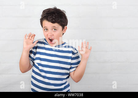 surprised child making a grimace on brick background Stock Photo