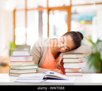 tired african female student sleeping on books Stock Photo