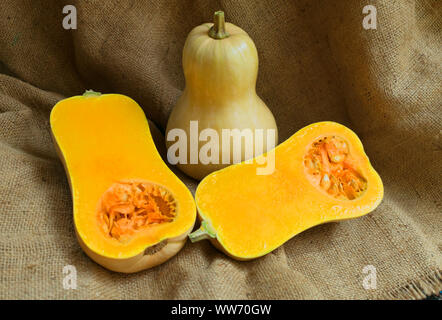 Whole and cut in half pumpkins on a brown background. Close-up. Autumn holidays concept. thanksgiving day. Stock Photo