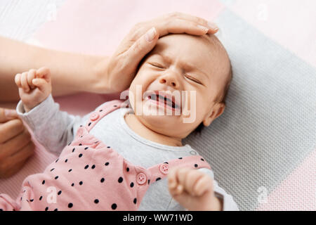mother's hand touching crying little baby daughter Stock Photo