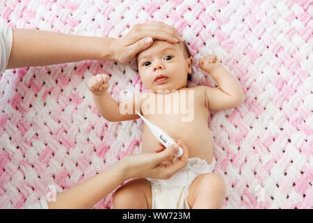 mother's hands measuring temperature of baby girl Stock Photo