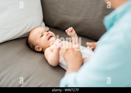 middle aged father changing baby's diaper at home Stock Photo
