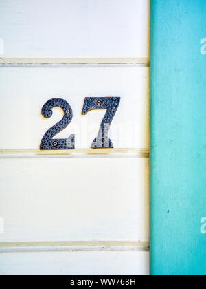 Vintage iron number 27 on a withe wooden wall. Stock Photo