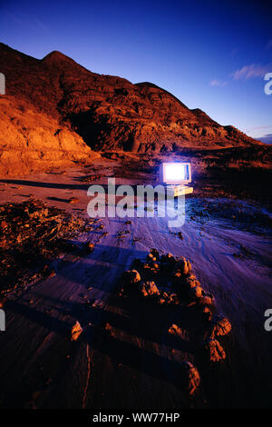 Outdated Computer in a desert landscape at dusk Stock Photo
