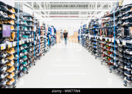 Abstract blur sport shoes on shelves in sneakers shop background. Blur of city shopping people at marketplace sneaker shopping store. Stock Photo