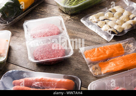 different types of packaged food. Meat, green beans, carrots and salmon on wooden table Stock Photo