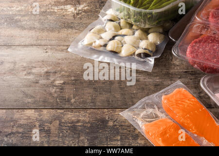 different types of packaged food. Beef,vegetables and seafood on wooden table. Copy space Stock Photo