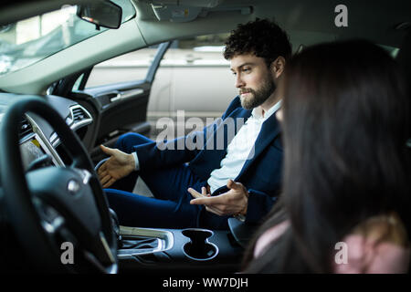 Successful young lady discussing her potential purchase with a car dealer Stock Photo