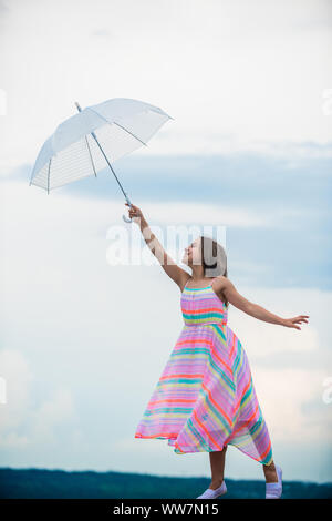 Dreaming about first flight. Kid pretending fly. I believe i can fly. Touch sky. Girl with light umbrella. Fairy tale character. Happy childhood. Feeling light. Anti gravitation. Fly drop parachute. Stock Photo