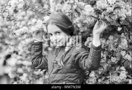 Little girl enjoy spring. Kid on pink flowers of sakura tree background. Kid enjoying pink cherry blossom. Tender bloom. Pink is the most girlish color. Bright and vibrant. Pink is my favorite. Stock Photo