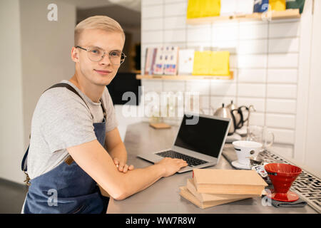 Happy young man in uniform and eyeglasses learning in front of laptop Stock Photo