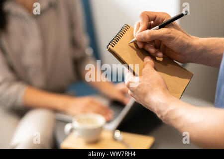 Young waiter going to write down order of client on blank page of notepad Stock Photo