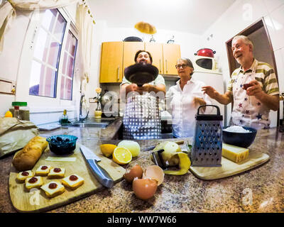 funny scene indoor at home in the kitchen woth a man that fly an omelette and fathers looking for it. everybody have fun in a crazy situation. family happyness concept Stock Photo