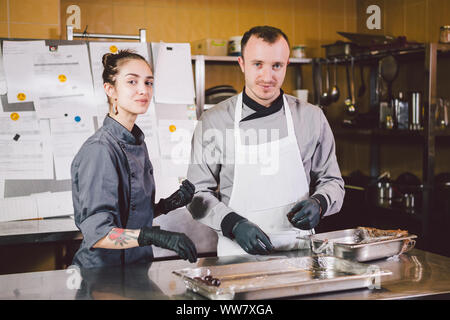 Cheerful Experienced Man And Woman Staff. Profession preparation confectionery products. Caucasian man and woman two employees colleague teamwork Stock Photo