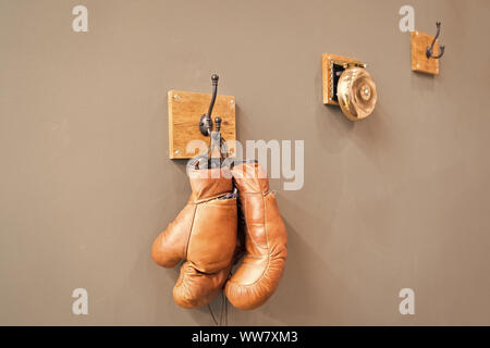 Museum of box sport. Box exhibition retro attributes. Boxing school. Final sparring. Vintage boxing gloves hang on hook wall background. Boxing gloves Stock Photo