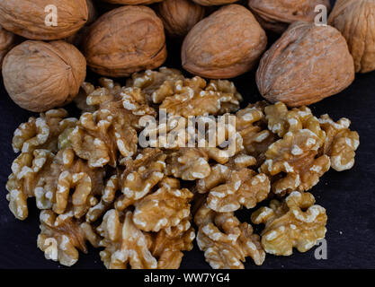 Walnuts, with and without shell,  on black surface Stock Photo