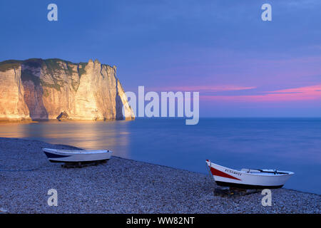 Fishing boats on the beach with view to Falaise d'Aval with Porte d'Aval in the dusk, Etretat, Seine-Maritime, English Channel, Normandy, France Stock Photo