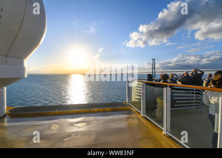 Tourists take photos on the upper deck as a cruise ship prepares to pass under the Oresund Bridge spanning the strait between Sweden and Denmark. Stock Photo