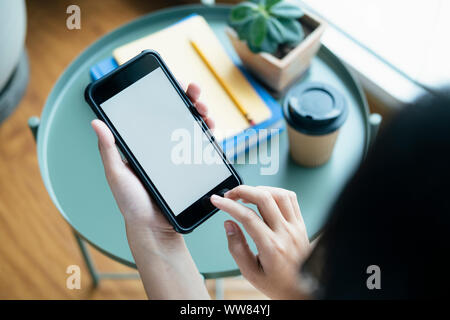 Closeup hands using smartphone mockup at the office desk. Blank screen mobile phone for graphic display montage. Stock Photo