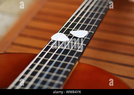 Music Concept: Guitar picks on the fingerboard of a brown guitar. Stock Photo