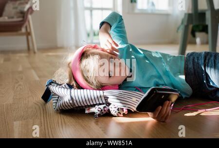 portrait of a young girl laying down listing to music with earphones Stock Photo