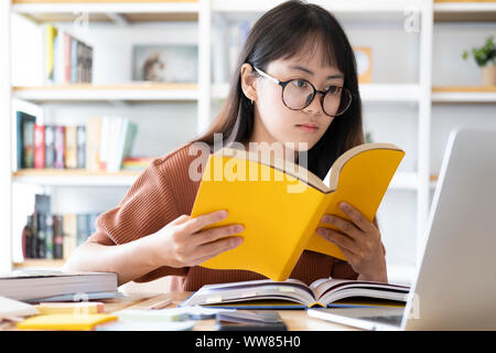 Education online learning or self study concept. Collage girl do reseaching and finding from books and internet online. Stock Photo