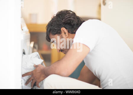 young man putting laundry in a washing mashine Stock Photo