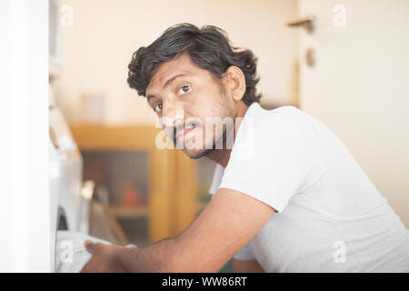 young man putting laundry in a washing mashine Stock Photo