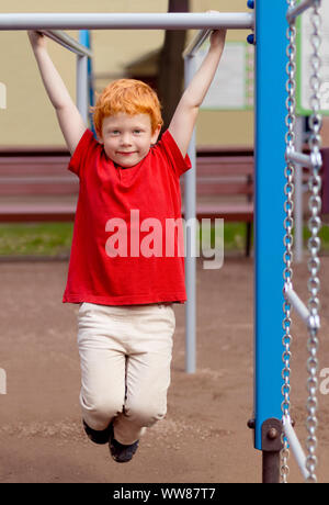 Boy on monkey bars. Little boy hanging on gym activity center of school playground. Outdoor activity for kids. Sport. Fashion kid. Cute boy in summer Stock Photo