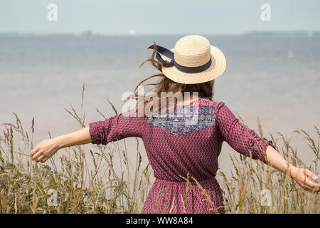 Young woman in summer dress and straw hat at the coast Stock Photo