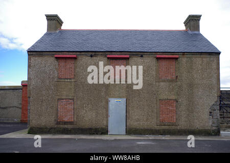 Disused building at Saltcoats Harbour, windows all bricked up. The harbour was designed by James Jardine in 1811. Stock Photo