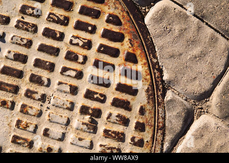 Abstract background of rusty manhole cover and paving tiles. Stock Photo