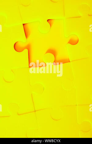 Multiple yellow puzzle pieces put together without one piece. View from above. Close up trendy monochrome image. Stock Photo