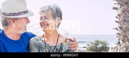 Happy senior couple laughing hugged on a summer day, concept of vacation, relaxation, rest, Behind it as a sea, ocean background Stock Photo