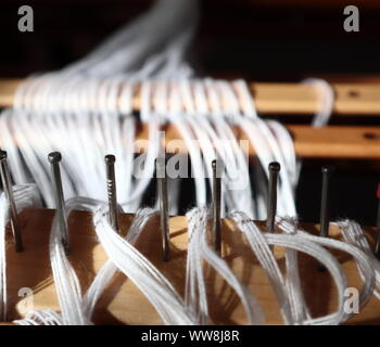 white cotton warp being dressed on the loom with a focus on the raddle (the bit with nails in it) Stock Photo