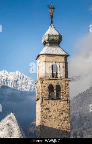 The bell tower of the ancient church of San Cipriano (St. Cyprian) in Taibon Agordino, on the background the Agner mountain, Belluno, Veneto, Italy