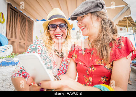 two girlfriends with smartphone laughing, people, happy having, fun together in relationship. summer style Stock Photo