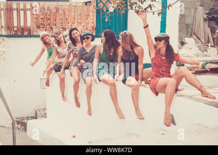 group of seven young smile beautiful woman crazy in vacation and friendship or relationship stay together sit down and go crazy with laugh. summer colors and bright image for joy concept Stock Photo