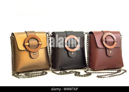 Gold brown, black and claret red colored collection of shoulder bags for women isolated on white background. Bags have wooden buckle and metal chain. Stock Photo